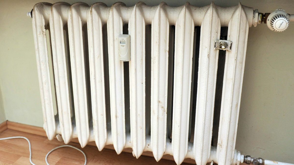 Biely radiátor s meračom tepla a termostatickým ventilom.