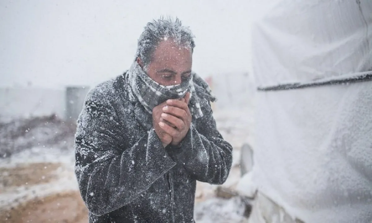 A man standing in the snow looking at his cell phone
